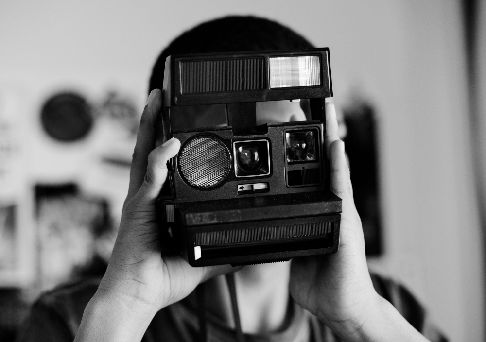 black and white photo with a human who holds a vintage camera on his hands.