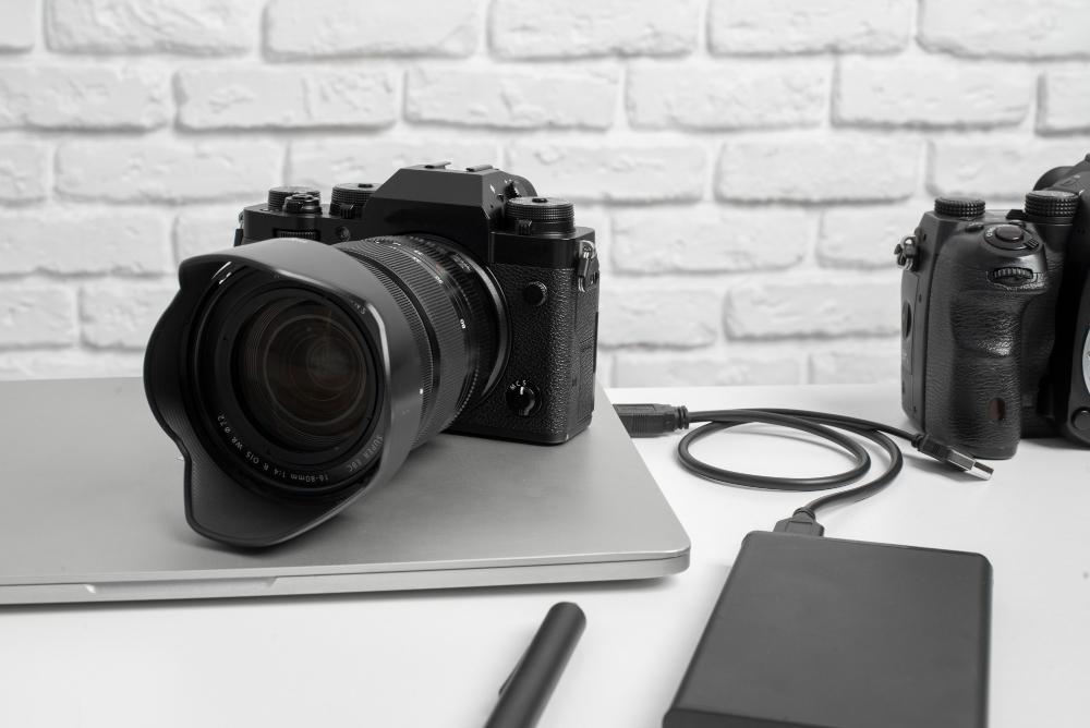 black-and-white photograph with a camera on a laptop computer charging from a power bank